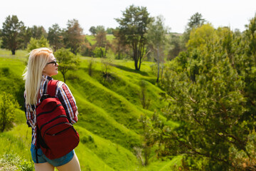 Naklejka premium Lifestyle summer image of pretty blonde hipster woman with bag pack traveling and enjoying, stylish fresh look, happy mood, sunny colors, travel concept, emotions.