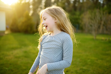 Fototapeta premium Cute little girl having fun outdoors on summer evening. Child exploring nature. Summer activities for kids.