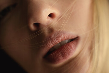 Crop female model in synthetic wig and with black lipstick showing teeth under colorful light