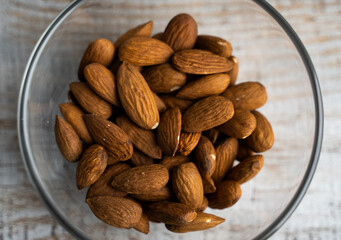 Almonds in a small plate on a vintage wooden table. Almond is a healthy vegetarian protein nutritious food. Natural nuts snacks.