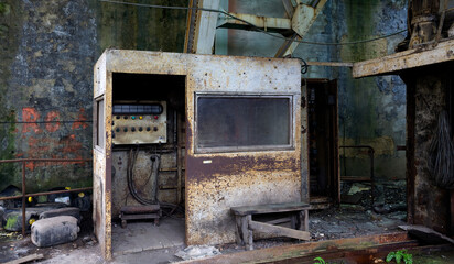 Rusty metal booth with electric equipment inside installed in old industrial building with grungy walls