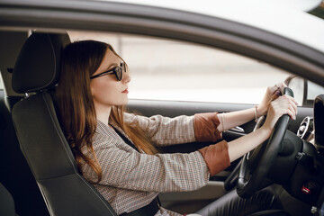 Obraz na płótnie Canvas Beautiful young girl sitting behind the wheel of a luxury car