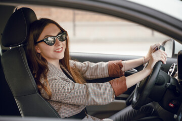 Beautiful young girl sitting behind the wheel of a luxury car