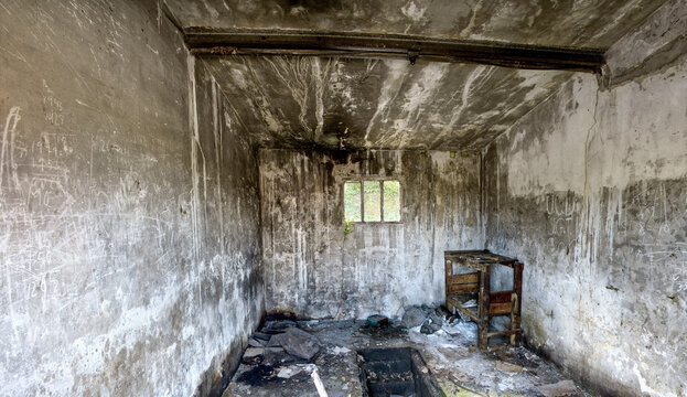 Empty small room with weathered concrete walls and dirty floor with remains of furniture inside derelict industrial building in Spain - Powered by Adobe