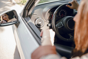 Fototapeta premium Beautiful young girl sitting behind the wheel of a luxury car