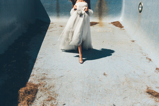 Sensual anonymous bride dancing in empty dirty pool