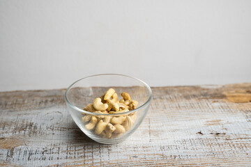 Cashew nuts in a small plate on a vintage wooden table as a background. Cashew nut is a healthy vegetarian protein nutritious food.