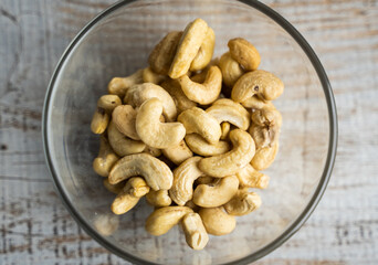 Cashew nuts in a small plate on a vintage wooden table as a background. Cashew nut is a healthy vegetarian protein nutritious food.