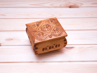 Wooden handmade closed jewelry box. Wooden table background. Vintage retro style.