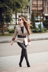 Fototapeta premium Beautiful young girl in a business suit on a background of business center. Business theme