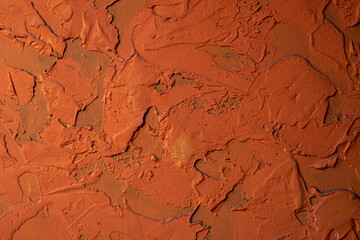 old concrete wall with a deep relief of bright orange paint with shadows. rough surface texture