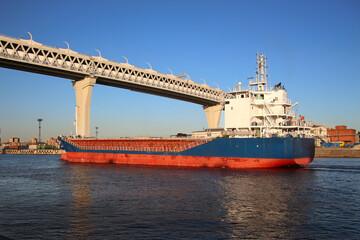 Fototapeta premium container cargo ship navigates a canal under a high-speed highway bridge