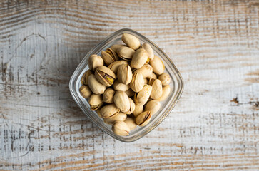 Pistachios in a small plate on a vintage wooden table. Pistachio is a healthy vegetarian protein nutritious food. Natural nuts snacks.