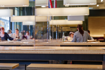 Selected focus view at temporary transparent acrylic partition on wooden table to make Social...