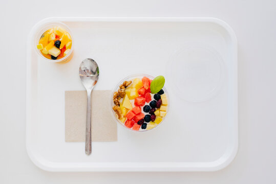 From above of bowl with yogurt and fruit placed on tray with spoon and napkin in self service cafe