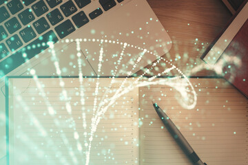 DNA hologram drawings over computer on the desktop background. Top view. Multi exposure. Concept...