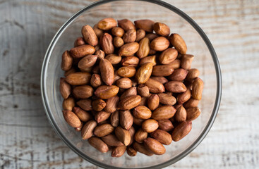 Peanut nuts in a small plate on a vintage wooden table. Peanuts nut is a healthy vegetarian protein nutritious food.