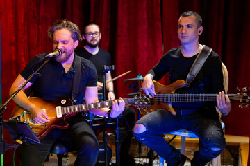 The Band of Musicians playing Electric Guitar, Bass Guitar and Drums during the Concert broadcast Online on Social media platforms in the Bar.