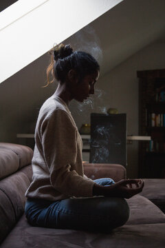 Side view of woman doing yoga while sitting on sofa at home