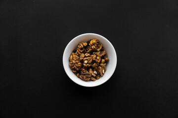 Walnut in a small plate on a black table. Walnuts is a healthy vegetarian protein nutritious food. Natural nuts snacks.