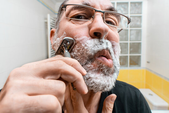 Bearded man shaving in bathroom