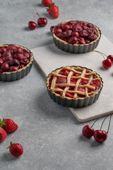 vegan tartlets with cherries and strawberries on a light gray background and marble board