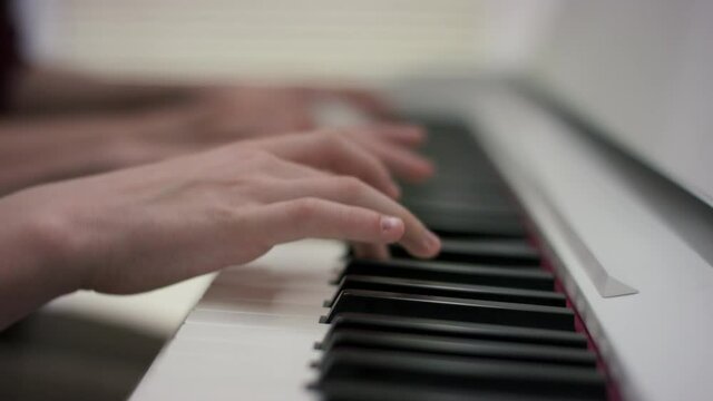 A side view close up showcase of the proccess of playing music on the white piano during a music lesson