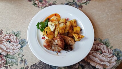 Fried chicken and home-cooked appetizing potatoes on a white plate