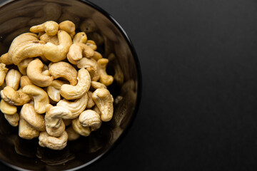 Cashew nuts in a small plate on a black table as a background. Cashew nut is a healthy vegetarian protein nutritious food.