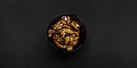 Walnut in a small plate on a black table. Walnuts is a healthy vegetarian protein nutritious food. Natural nuts snacks.