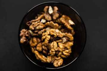 Walnut in a small plate on a black table. Walnuts is a healthy vegetarian protein nutritious food. Natural nuts snacks.