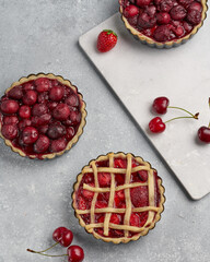 vegan tartlets with cherries and strawberries on a light gray background and marble board