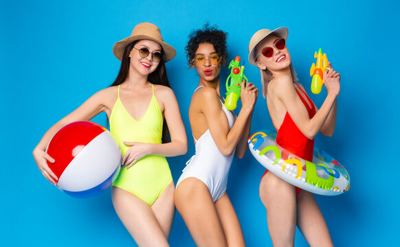 Young Girls In Swimsuits Having Fun With Swim Toys Over Blue Background