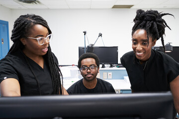 Black women and man in uniform discussing data on computer while working in contemporary laboratory together