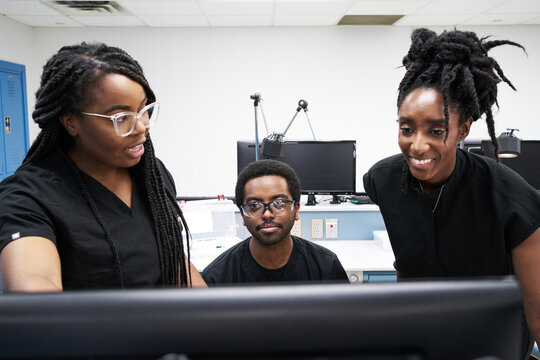 Black women and man in uniform discussing data on computer while working in contemporary laboratory together - Powered by Adobe