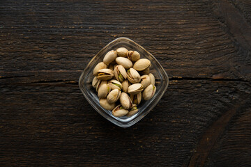 Pistachios in a small plate on a vintage wooden table. Pistachio is a healthy vegetarian protein nutritious food. Natural nuts snacks.