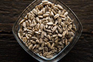 Sunflower seeds in a small plate on the wooden vintage table. Healthy vegetarian protein nutritious food. Sunflower seed on rustic old wood.
