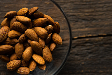 Almonds in a small plate on a vintage wooden table. Almond is a healthy vegetarian protein nutritious food. Natural nuts snacks.