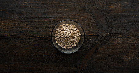 Fototapeta na wymiar Sunflower seeds in a small plate on the wooden vintage table. Healthy vegetarian protein nutritious food. Sunflower seed on rustic old wood.