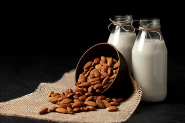 almond milk in bottles with nuts on a black table, a variety of dairy products without sugar and lactose, a vegetarian drink
