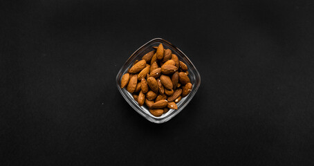 Almonds in a small plate on a black table. Almond is a healthy vegetarian protein nutritious food....