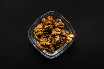 Walnut in a small plate on a black table. Walnuts is a healthy vegetarian protein nutritious food. Natural nuts snacks.