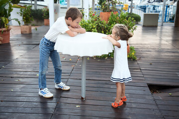 A boy and a girl speek standing at the table.