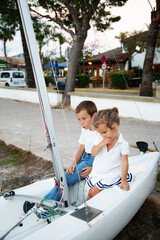 Two siblings are on a white boat.