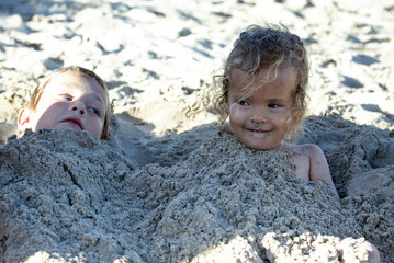 Two kids in the sand on the beach. Muro. Majorca.