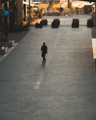 A lonely man walks along a paved built-up city area