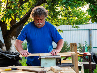 Carpenter using circular saw for cutting wooden plank