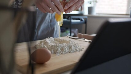 Panning shot, Woman Cracking Eggs into a Flour Well. Making Dough at Home in Slow Motion