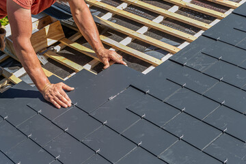 Craftsmen are installing a slate roof home.Professional roof workers repairing roof t.Working on rooftop. - obrazy, fototapety, plakaty