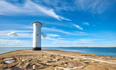 Panoramic image of seawall and old whitewashed windmill lighthouse in Swinoujscie, a port in Poland on the Baltic Sea. - obrazy, fototapety, plakaty